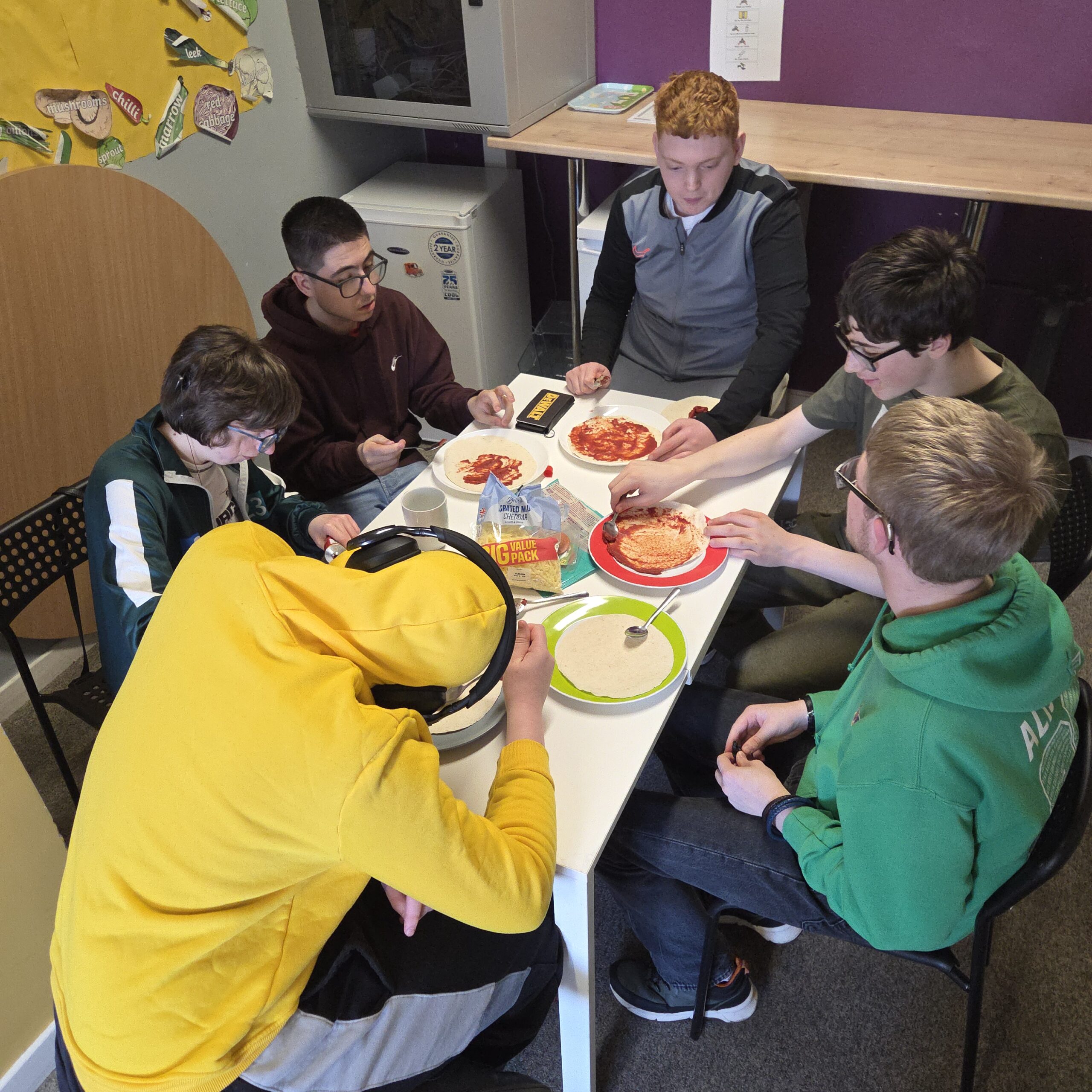 Young people preparing pizzas together during a cooking session