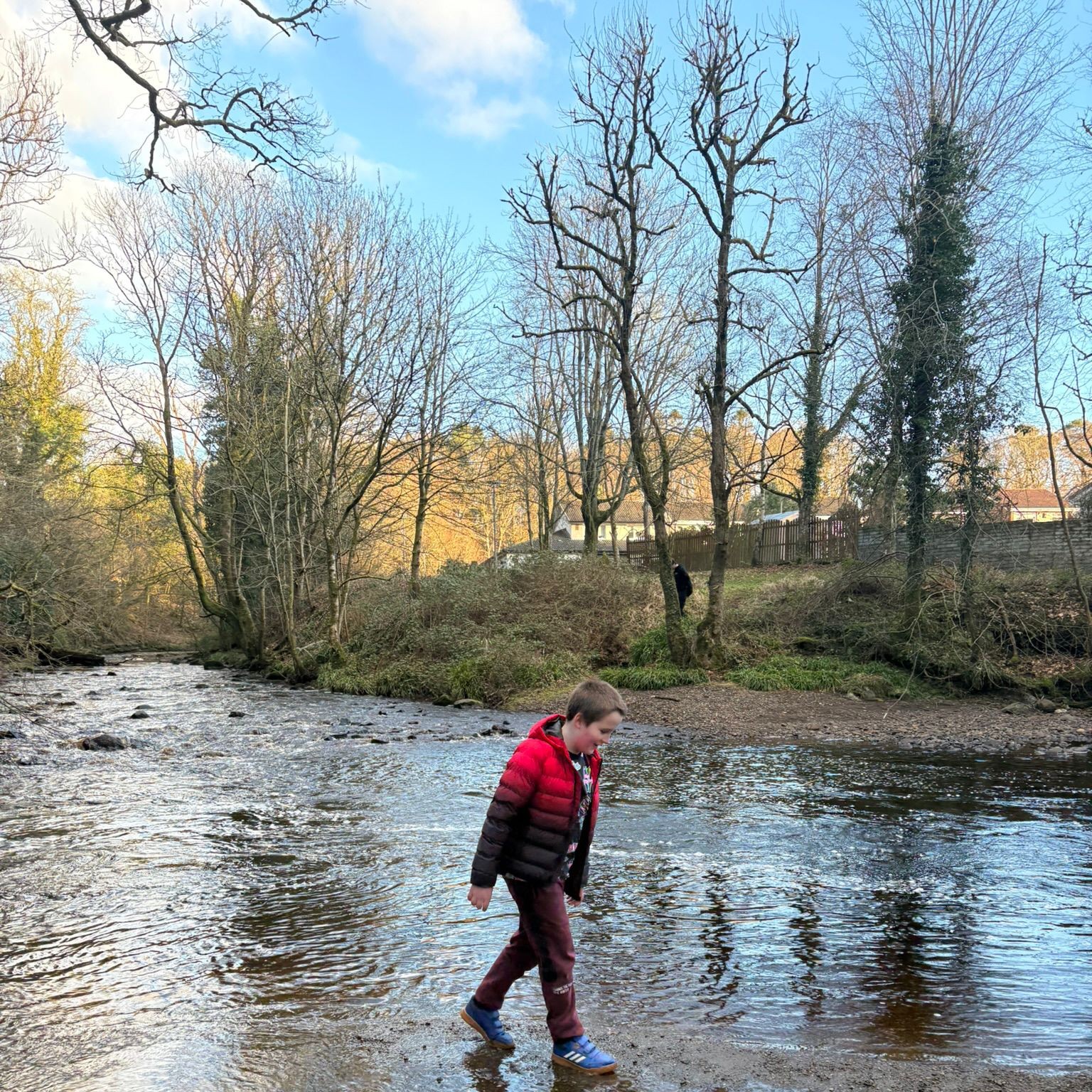 Young person exploring a shallow river during an outdoor wellbeing activity