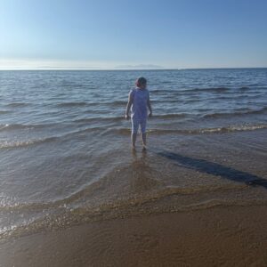 Young person enjoying a calm outdoor wellbeing activity at the beach